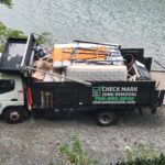 looking down on lakeside junk removal truck full of mattresses and debris
