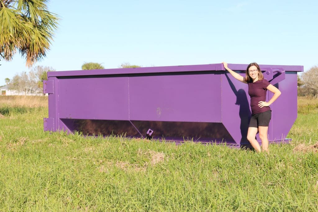 A photo of a woman standing next to a 15 yard dumpster rental from Chickadee.